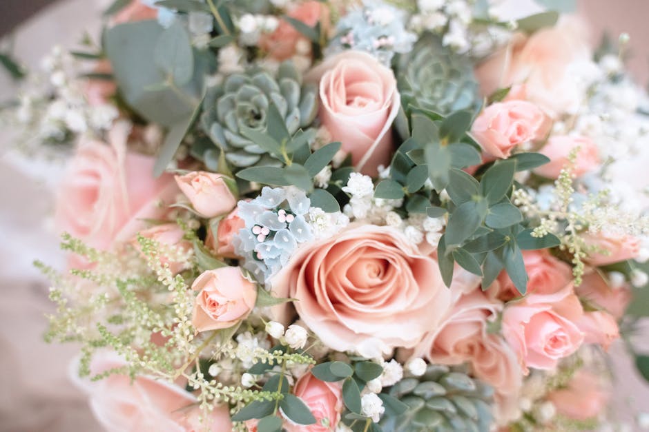 A close-up image of a floral arrangement featuring large, soft pink roses with gently curled petals, complemented by smaller pink rosebuds and sprigs of delicate white baby's breath. The bouquet is ad